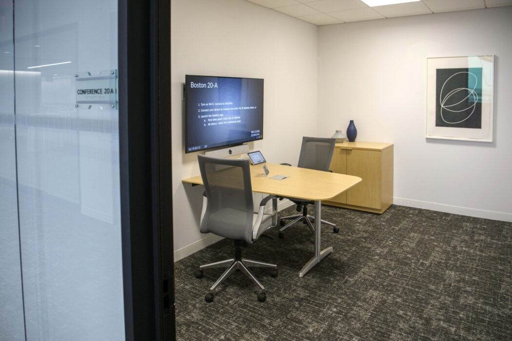 Small conference room containing small table, two chairs, and television for videoconferencing.