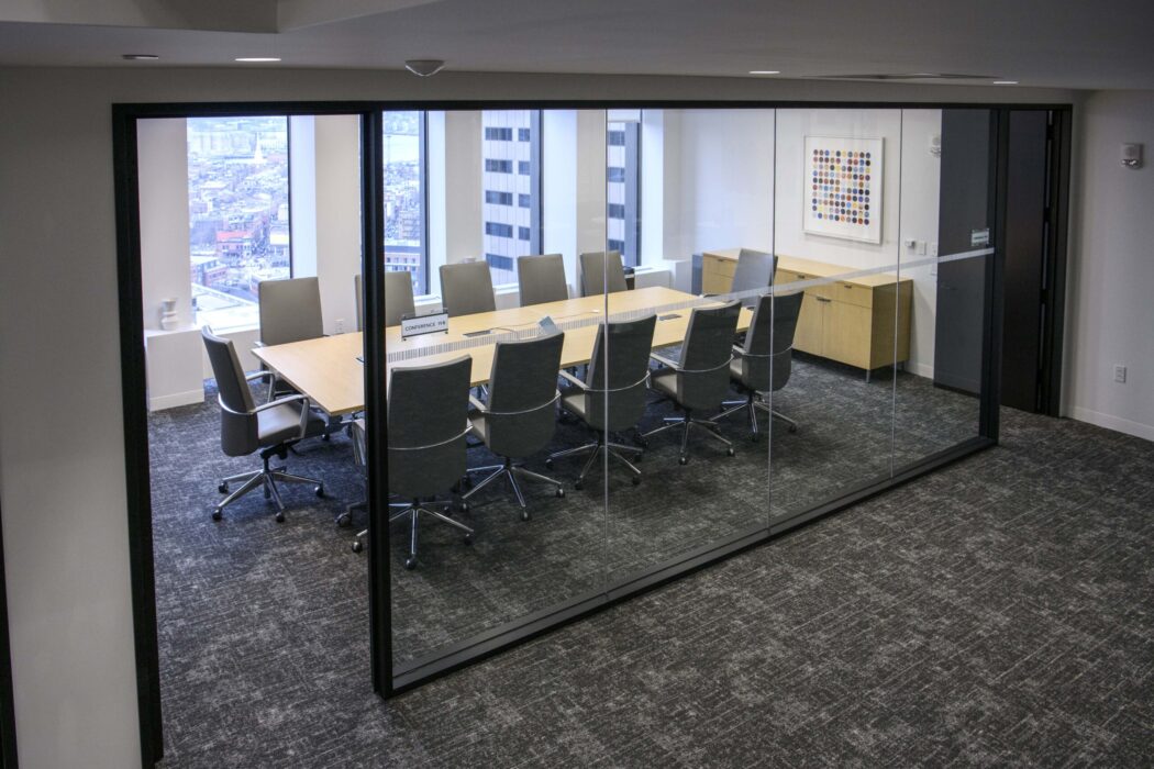 Conference room containing large conference table, ten chairs, and large windows.