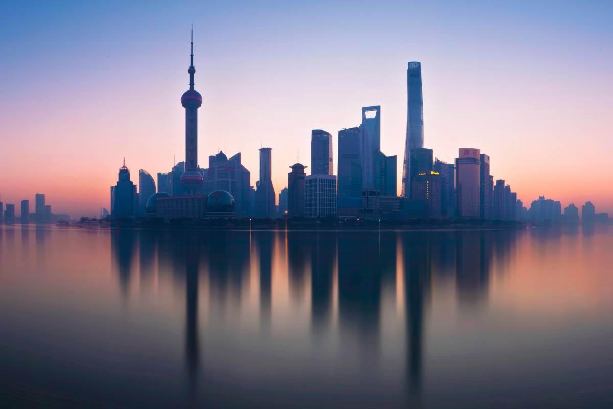 Photo of the Shanghai skyline at dusk, with reflection in the water.